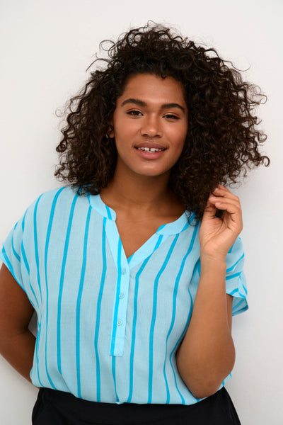 Billede af en model med en lyseblå t-shirt, med lodrette blå striber. T-shirten har V-udskæring og knapper. 