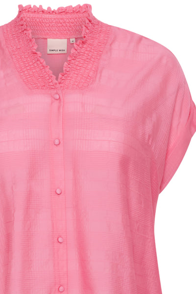 Nærbillede af kortærmet bluse fra Simple Wish, i en flot pink farve. Der er her fokus på blusens flotte hals, som har en smock kant. Blusen har v-udskæring og er gennemknappet.